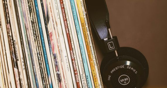 Black headphones resting against a row of vintage vinyl record albums, illustrating Amazon's cloud music service