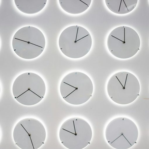 A white wall with many clocks on it, illustrating cloud computing needing to deliver results