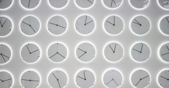 A white wall with many clocks on it, illustrating cloud computing needing to deliver results