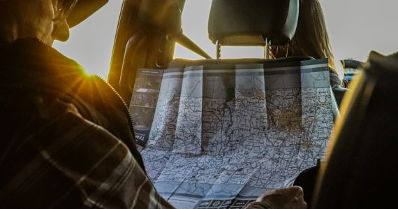 Man studying a map in a car at sunset, illustrating creating a cloud roadmap