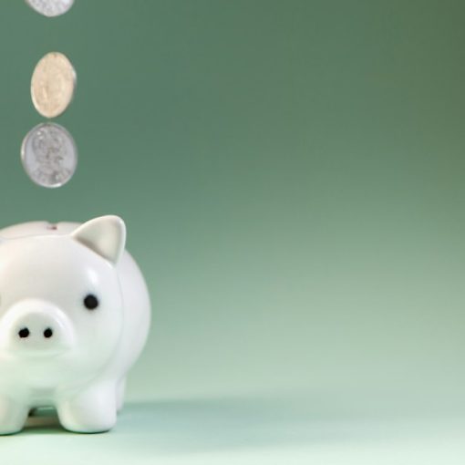 Coins falling into a white piggy bank, illustrating cloud computing cost savings