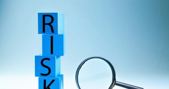 Blocks spelling risk next to a magnifying glass, illustrating shadow IT financial risk