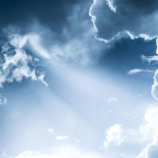 Bright light filtering through dense blue clouds in a vast sky, illustrating the upside of cloud computing