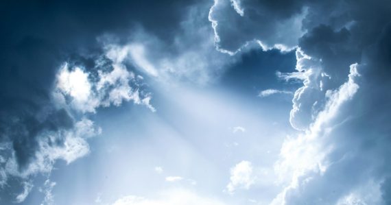 Bright light filtering through dense blue clouds in a vast sky, illustrating the upside of cloud computing