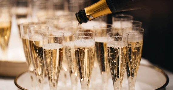 Champagne pouring from a bottle into a group of flutes on a tray, illustrating funding for cloud computing startups