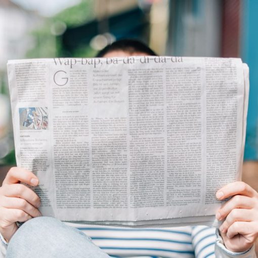 Man sitting on bench reading newspaper, illustrating Sunday cloud computing statistics