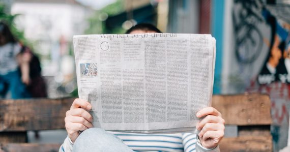 Man sitting on bench reading newspaper, illustrating Sunday cloud computing statistics