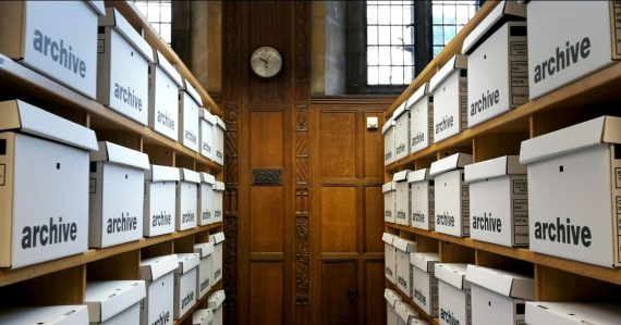 Rows of white archive boxes on wooden shelves, illustrating how businesses use cloud storage