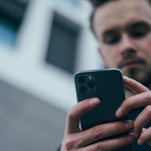 Man wearing black sweater using smartphone, illustrating BlackBerry and Microsoft cloud partnership