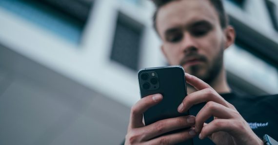 Man wearing black sweater using smartphone, illustrating BlackBerry and Microsoft cloud partnership