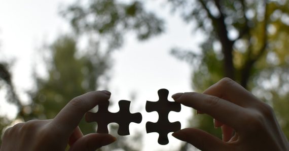 A person holding two pieces of a puzzle, illustrating service-oriented architecture and cloud success