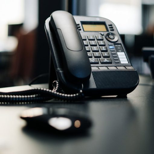 Black ip desk phone on black wooden table, illustrating cloud VoIP services