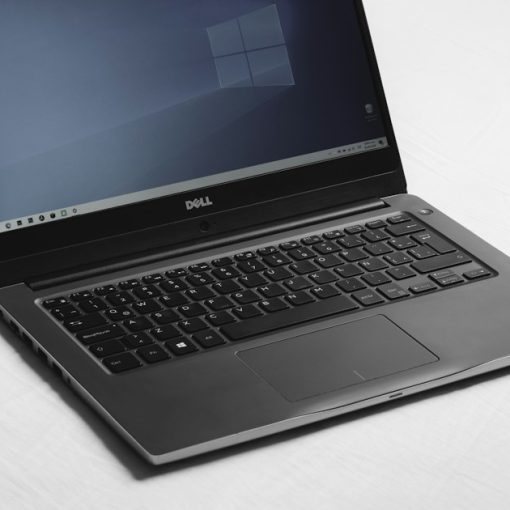 Laptop with a blue desktop screen on a white surface, illustrating virtual desktops