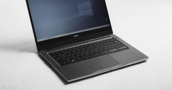 Laptop with a blue desktop screen on a white surface, illustrating virtual desktops