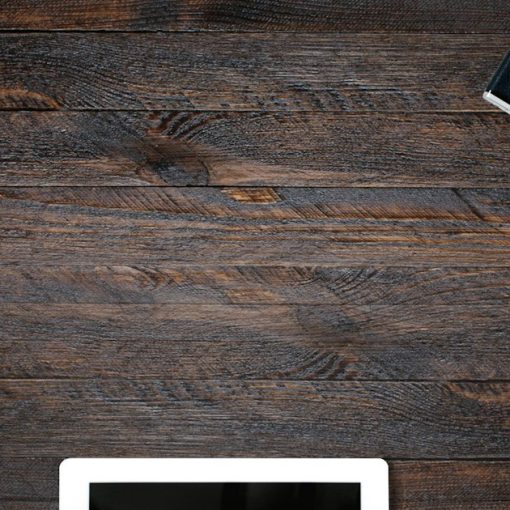 A laptop, tablet, smartphone, camera, and glasses on a dark wooden desk, illustrating IT consumerisation as an opportunity