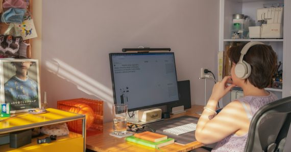 A person wearing headphones at a desk with a computer in a home office, illustrating contact centers adopting home working