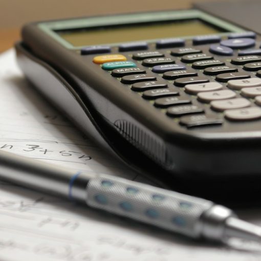 A calculator and a pen on a piece of paper, illustrating using cloud computing to control costs