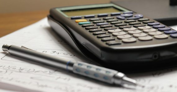 A calculator and a pen on a piece of paper, illustrating using cloud computing to control costs