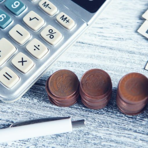 A calculator, pen, and money on a table, illustrating the cost advantage debate over cloud computing