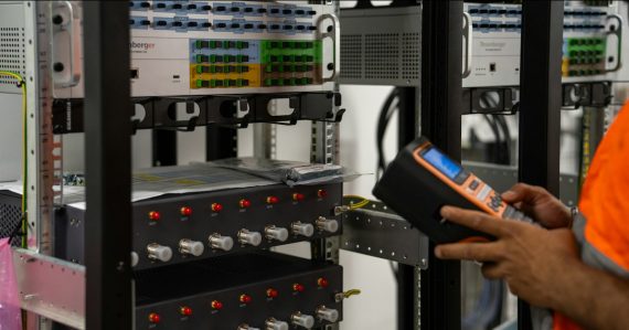 Technician inspecting server racks with a handheld diagnostic tool, illustrating a cloud computing data center