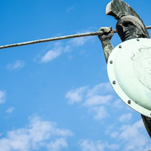 Bronze warrior statue with spear and shield under blue sky, illustrating defending the cloud after outages