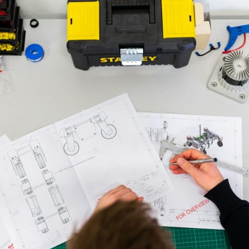 A person using a caliper to measure technical engineering drawings, illustrating cloud computing for design engineers