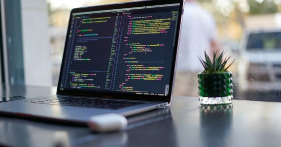 Laptop showing programming code on a café table, illustrating DevOps in the cloud