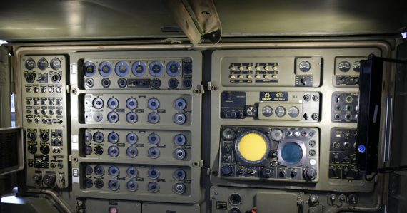 Complex control panel with many buttons and screens, illustrating Department of Defense cloud computing