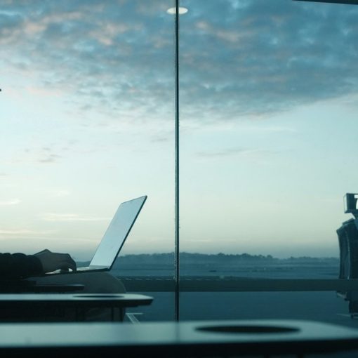Man working on laptop by an airport window at sunrise, illustrating mobility driving desktop virtualization