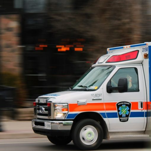 White and blue ambulance van traveling on road, illustrating E911 location for enterprise phone systems