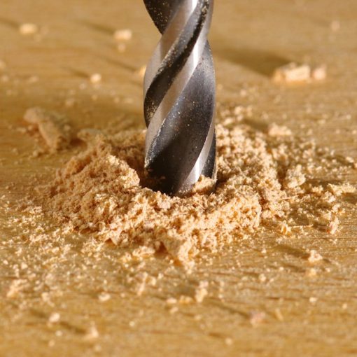 A drill being used to drill a piece of wood, illustrating business outcomes over technical specs