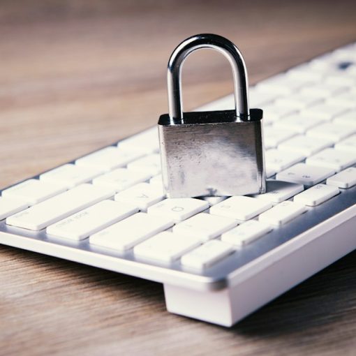 Padlock resting on a white computer keyboard, illustrating steps to secure cloud computing