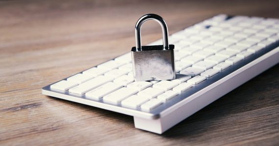 Padlock resting on a white computer keyboard, illustrating steps to secure cloud computing