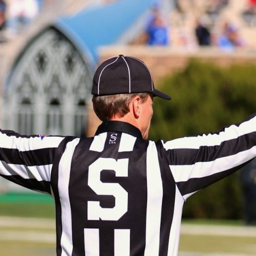 A referee standing on a field with his hands in the air, illustrating functional IT teams in a virtualized world
