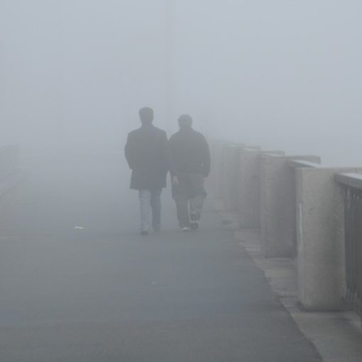 Two people walking on a bridge in the fog, illustrating the evolving role of the CIO in the cloud