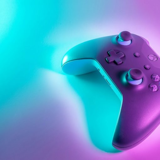A wireless game controller lit by cyan and magenta neon light, illustrating cloud gaming power