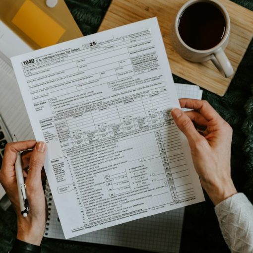 Hands holding tax forms with calculator and laptop, illustrating H&R Block's thin client virtualization