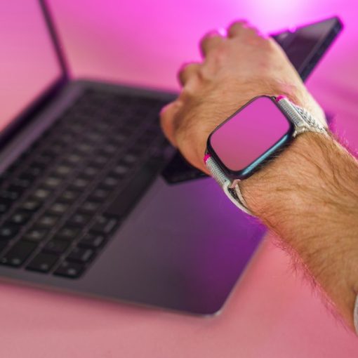 A man holding a smart phone while using a laptop, illustrating businesses adopting hosted PBX