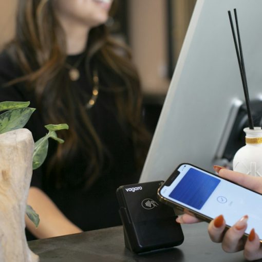 A woman sitting at a desk using a cell phone, illustrating hosted PBX for business phone systems
