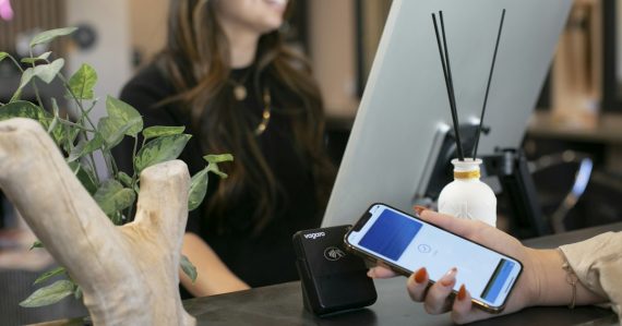 A woman sitting at a desk using a cell phone, illustrating hosted PBX for business phone systems