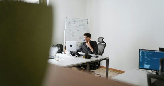 Man in black suit sitting on black office rolling chair, illustrating hosted voice services