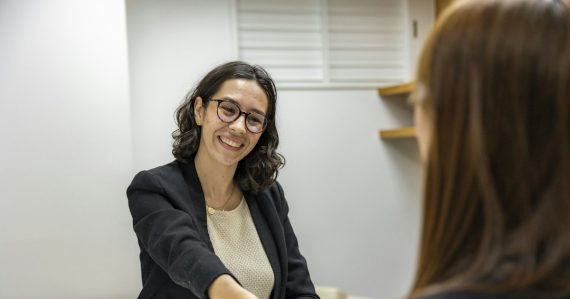 HR manager shaking hands with a candidate across a table, illustrating HR managing cloud computing risk