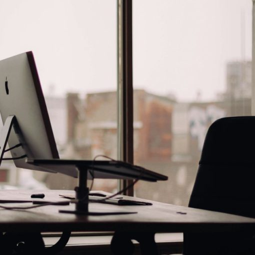 Silver iMac on desk inside office, illustrating the cloud shrinking the office