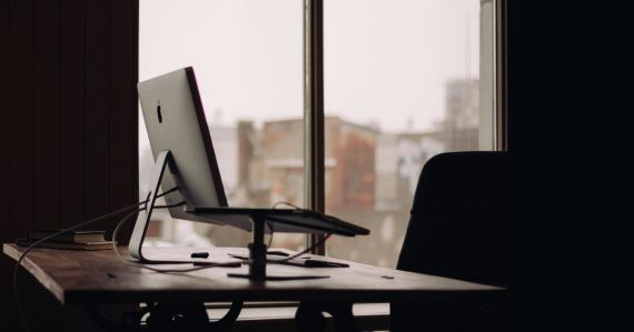 Silver iMac on desk inside office, illustrating the cloud shrinking the office
