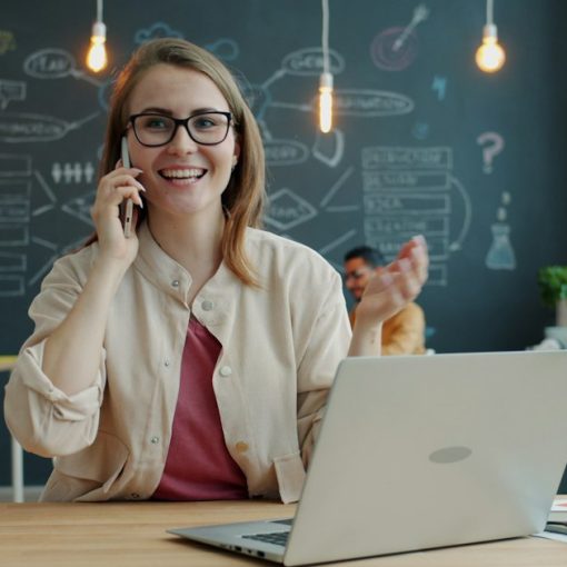 Smiling woman talking on phone in modern office, illustrating IP telephony for small business