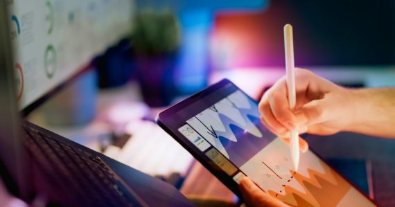 Person using stylus on tablet with charts, illustrating the iPad's role in desktop virtualization