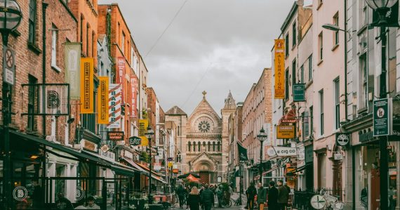 A group of people walking down a street next to tall buildings, illustrating Ireland's cloud computing opportunity