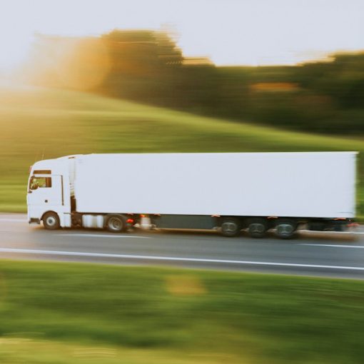 White semi truck driving down a rural road, illustrating cloud computing for transport and logistics