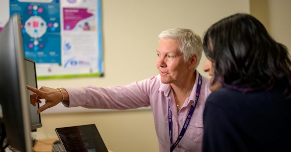 Colleagues working together at a computer, illustrating key skills IT pros need for cloud computing