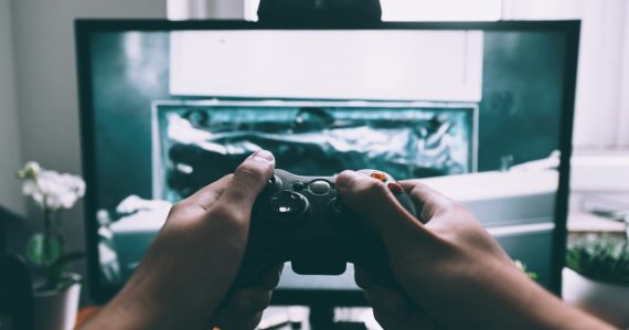 Person holding game controller in-front of television, illustrating Kinect and the future of cloud computing